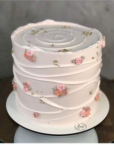 a white cake with pink flowers and gold sprinkles on it's side