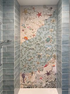 a bathroom with blue tiles and sea creatures on the wall, along with a white bathtub