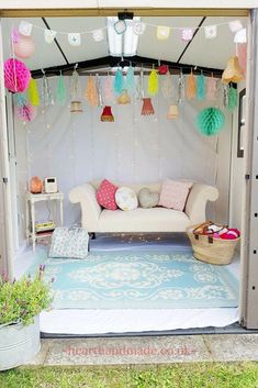 a white couch sitting under a tent with paper lanterns hanging from it's ceiling