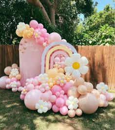 a bunch of balloons that are sitting in the grass next to a building and fence