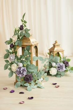 two small wooden lanterns with flowers and greenery on the floor next to each other