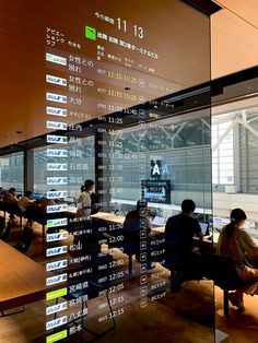 people are sitting at desks in an office with large numbers on the glass wall