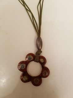 a necklace with an oval shaped pendant hanging from it's side on a white surface