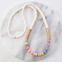 Get ready for summer with this wood beaded necklace! A mix of natural wood and bright heishi beads and in an easy pull-over-the-head style, these are sure to brighten up all your shorts-and-flip-flops looks. HEISHI & WOOD BEAD NECKLACES + 8mm wooden beads - choose cream, whitewash, tan, or natural + vinyl heishi beads in a random pattern + gold-plated crimp with bead closure for a pull-over-the-head style + 28 inches long + all Libby & Smee necklaces come packaged in a clear resealing bag for st Cheap Rainbow Heishi Beads Jewelry, Cheap Heishi Beads Necklaces For Vacation, Cheap Colorful Heishi Bead Necklaces, Cheap Green Necklace With Heishi Beads, Heishi Beads Wooden Necklaces, Adjustable Beaded Necklace With Wooden And Heishi Beads, Beach Wooden And Heishi Beads Necklaces, White Wooden Beaded Necklaces For Beach, Boho Beaded Necklace