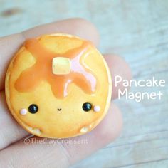 a hand holding a tiny yellow donut with icing on it's face