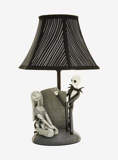 a lamp that is on top of a table with a skeleton sitting next to it