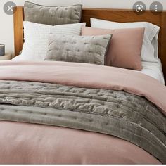 a bed with pink and grey linens in a bedroom