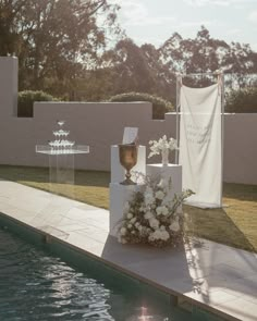 an outdoor ceremony set up with flowers and candles on the side of a swimming pool