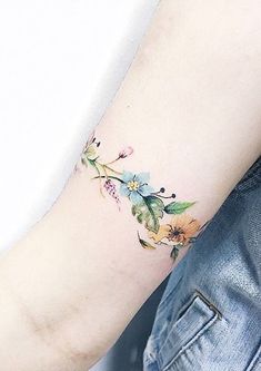 a woman's arm with flowers and leaves on the side of her body,