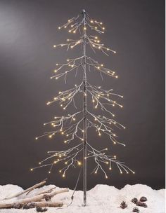 a lighted christmas tree in the snow with white lights on it's top and branches