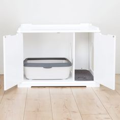 a cat litter box sitting on top of a hard wood floor next to a white wall