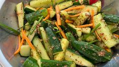 a metal bowl filled with cucumbers and carrots