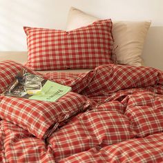 a red and white checkered comforter on a bed with two pillows next to it