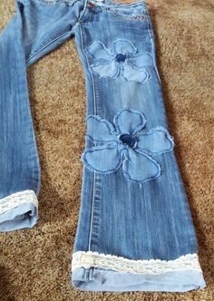 an old pair of jeans with flower appliqued on the side, laying on carpet