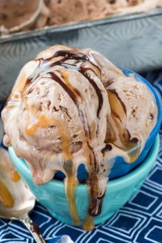 two scoops of ice cream with caramel drizzle on top in a blue bowl