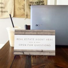 a table with a sign that says real estate agent here open for questions next to a laptop