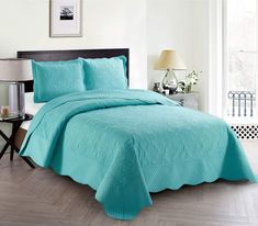 a bedroom with a bed covered in a turquoise bedspread and matching comforter