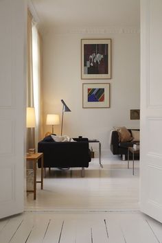 a living room filled with furniture and pictures on the wall above it's doorway