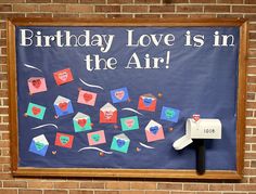 a birthday love is in the air sign on a brick wall with mailboxes