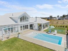 an aerial view of a house with a swimming pool in the foreground and lawn area