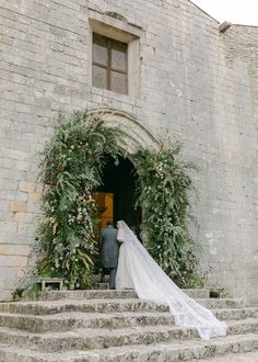 a bride and groom are standing on the steps in front of an old stone building