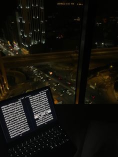 a laptop computer sitting on top of a desk in front of a window at night