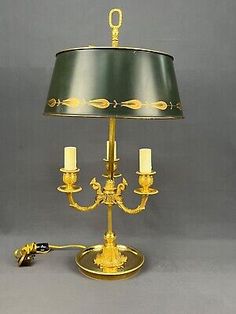 an antique brass plated candelabra with two candles and a green shade