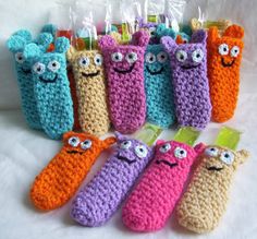 crocheted toothbrush holders with eyes and mouths on them are lined up in rows