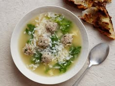 a bowl of soup with meatballs and parmesan cheese next to toasted bread