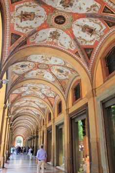 the ceiling is decorated with intricate paintings and designs on it's sides, along with two men walking down one side