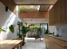 an open kitchen and dining room area with wooden cabinets, counter tops, and potted plants