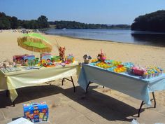 two tables on the beach are set up with food and drinks for an outdoor party