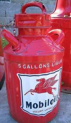 a red gas can sitting next to an old car