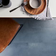 an overhead view of a table with two coffee cups and a wooden plate on it