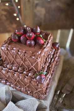 a chocolate cake with strawberries and chocolate icing on top is sitting on a table