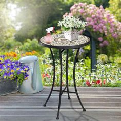 an outdoor table with flowers and watering can