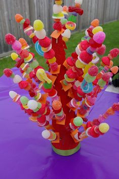 a vase filled with gummy bears sitting on top of a purple table covered in candy