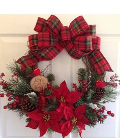 a christmas wreath with poinsettis and pine cones hanging on the front door