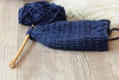 a blue knitted hat sitting on top of a wooden floor next to a ball of yarn