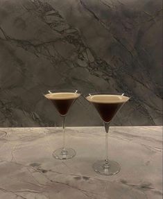 two martini glasses sitting on top of a marble counter