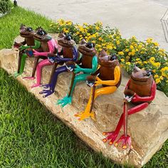 colorful frog figurines sitting on a rock in the grass