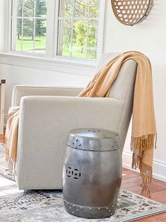 a living room with a chair, ottoman and rug in front of a window on the floor