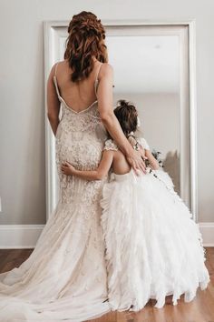 a woman in a wedding dress helping another woman get dressed