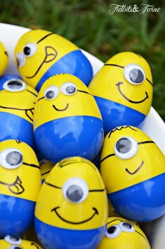 there are many yellow and blue eggs with faces painted on them, sitting in a white bowl