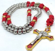 This beautiful rosary is made with 500 red paracord.   The crucifix is a red enamel with gold trim and silver Jesus.   It goes beautifully with the brass Our Father's and stainless steel Hail Mary's.   The center is nickle and has a crucifix on the front to go with both sets of beads and the St. Benedict medal on the crucifix.   The rosary has two sets of stainless steel split rings on either side of the center for the Saint medals of your choice. This rosary is not intended to be worn as a necklace, but to be prayed with reverence.   If you want a rosary that you can wear around you neck to pray, please contact me for a custom order. Adjustable Red Rosary With 8mm Beads, Red Adjustable Rosary With Round Beads, Adjustable Red Rosary With Round Beads, Adjustable Red Rosary, Adjustable Red Cross Necklace, Red Adjustable Cross Necklace, Split Jump, Paracord Rosary, Saint Medals