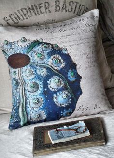 a decorative pillow on a bed next to a book