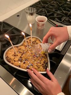 someone is lighting candles on a cookie in the shape of a heart