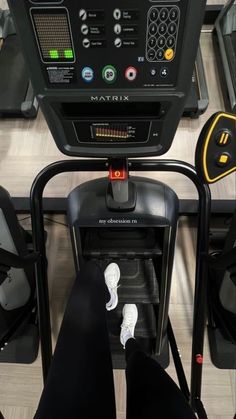 there is a person that is sitting on a treadmill in the gym with their feet up