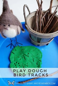 play dough bird tracks on a blue plate next to a basket with sticks in it