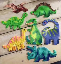 the perler bead dinosaurs are all different colors and sizes, including green, blue, red, yellow, orange, and purple